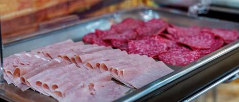 A display case with sliced meats, including ham and salami.