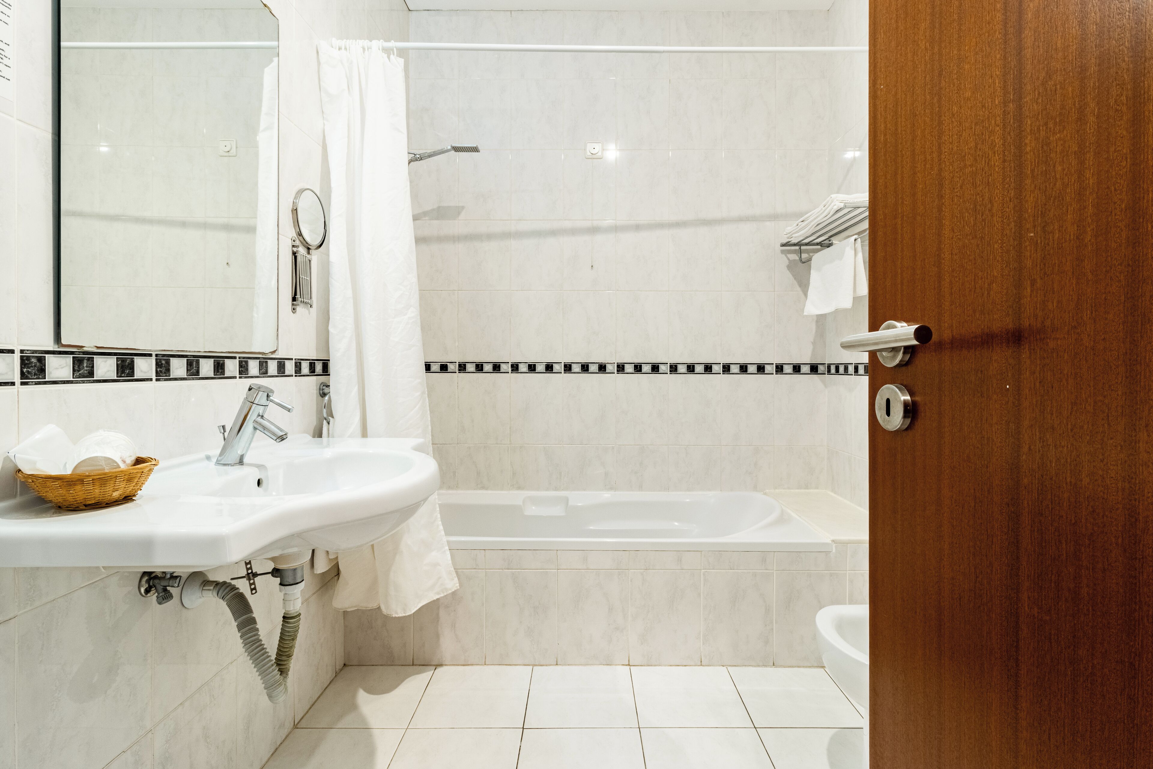 A bathroom with a sink, mirror, and bathtub.