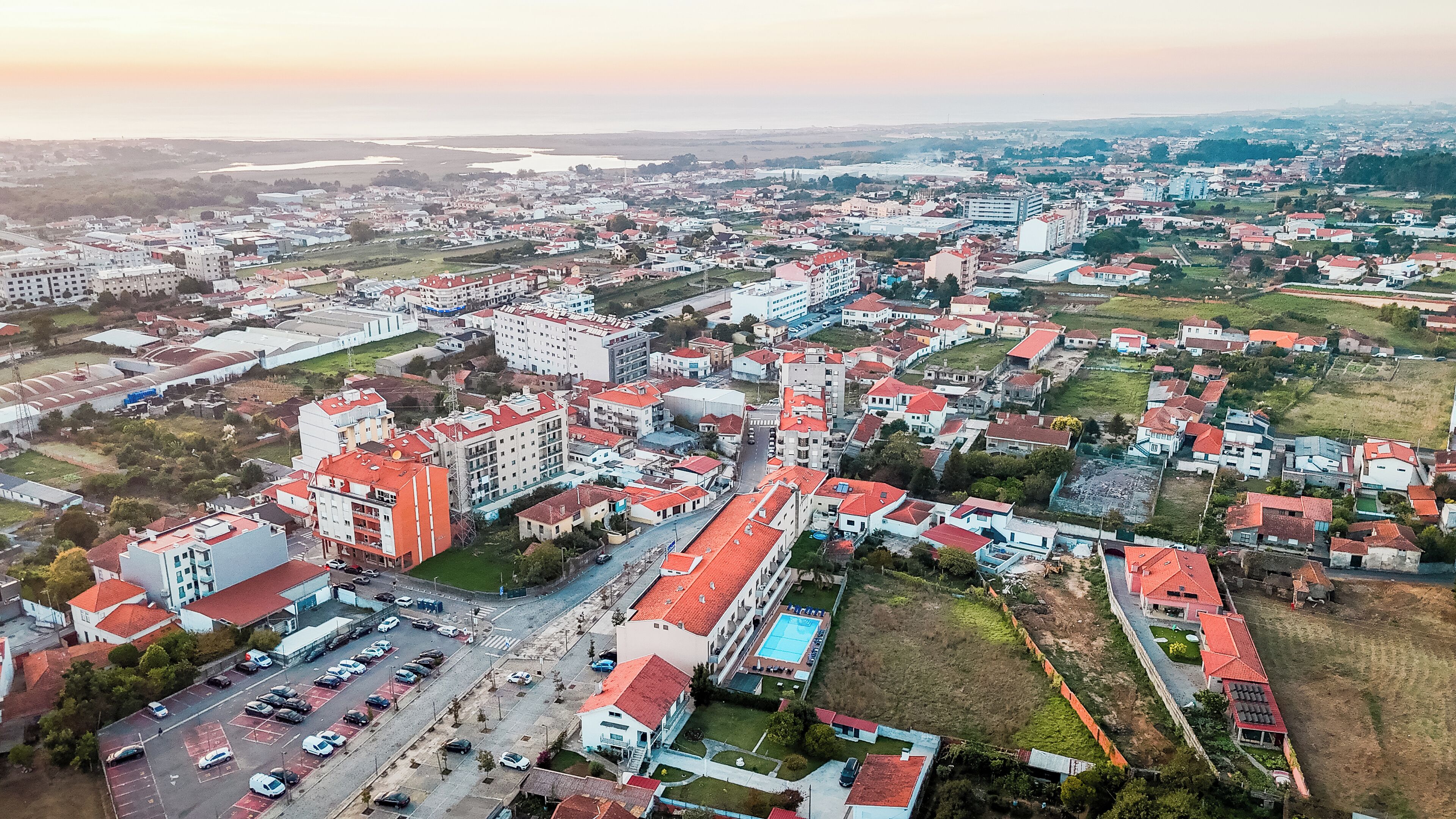 Vista aerea di una zona residenziale con diversi edifici, strade e una piscina.