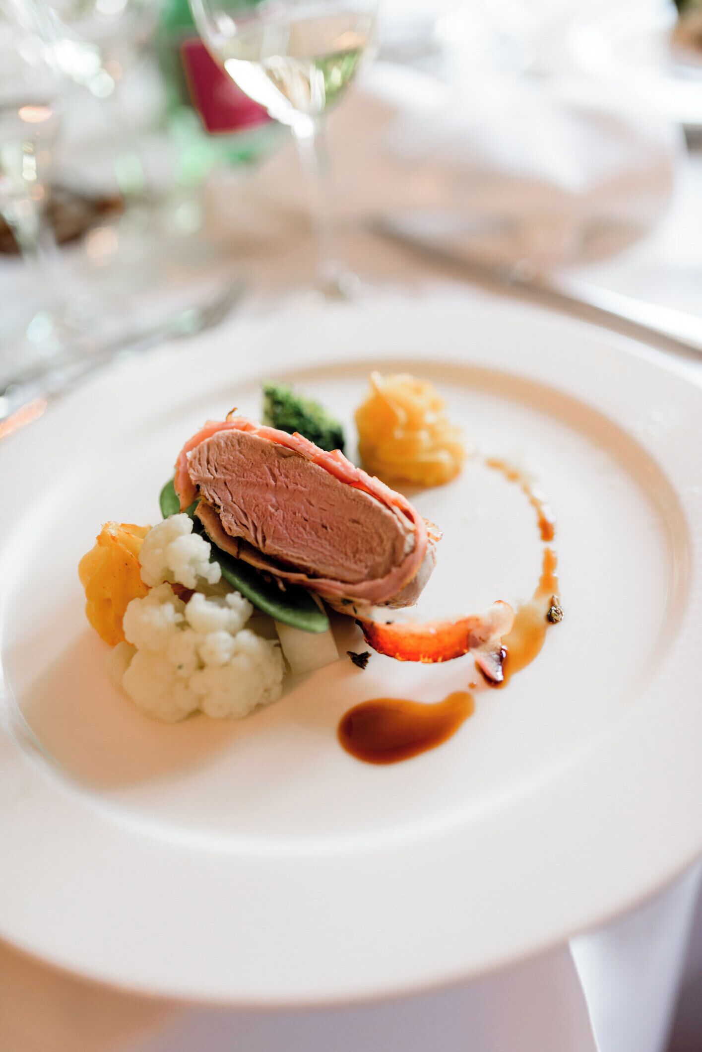 A plate with a slice of meat, cauliflower, and a sauce.