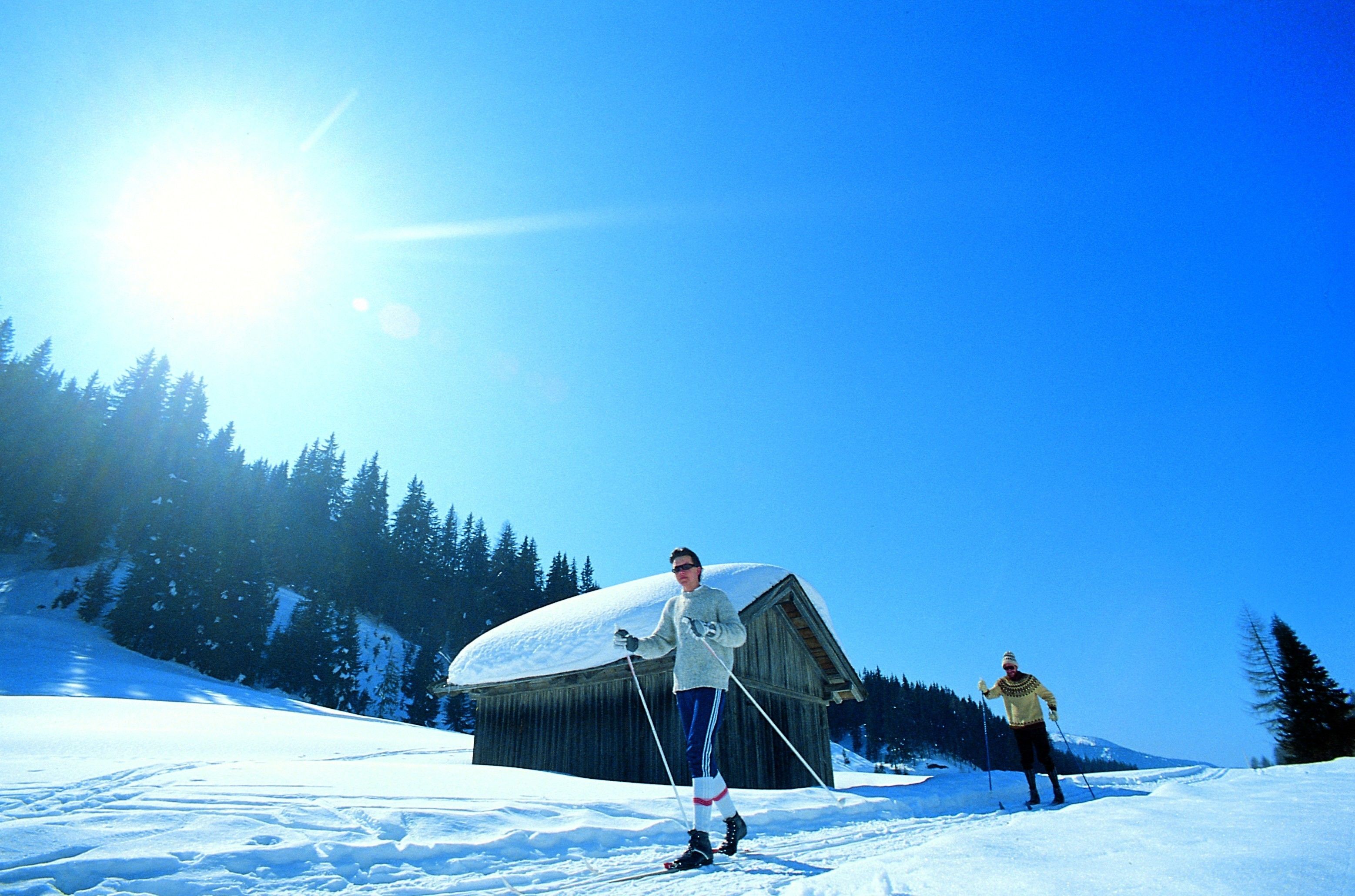 A wooden cabin in a snowy landscape with a clear sky.