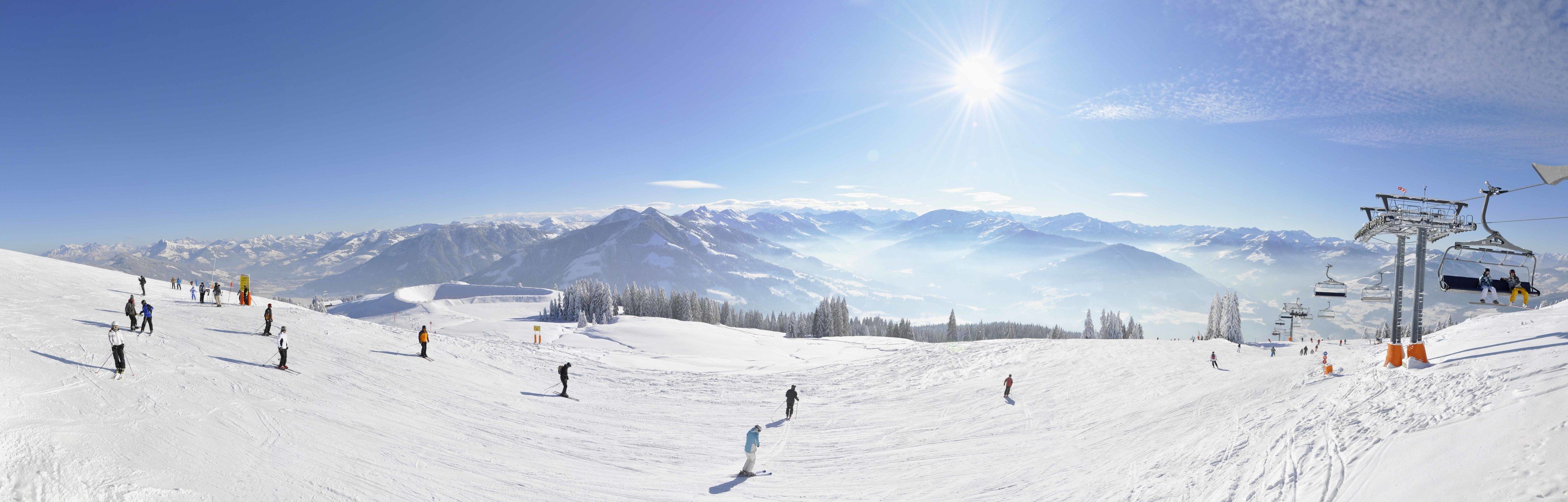 A snowy ski slope with skiers and a ski lift.