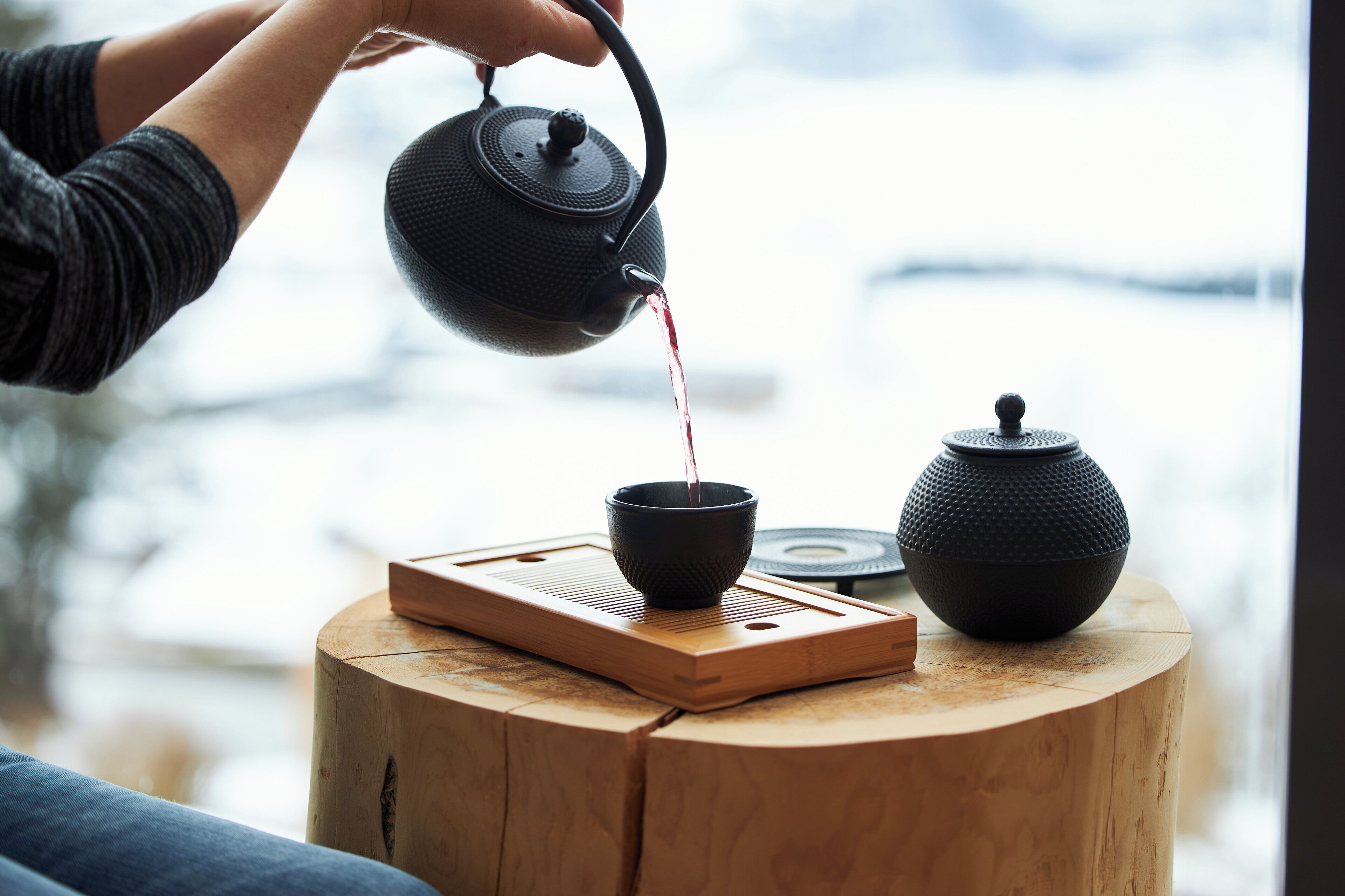Ein Holztisch mit Teekanne und Tasse sowie ein Holzschemel.