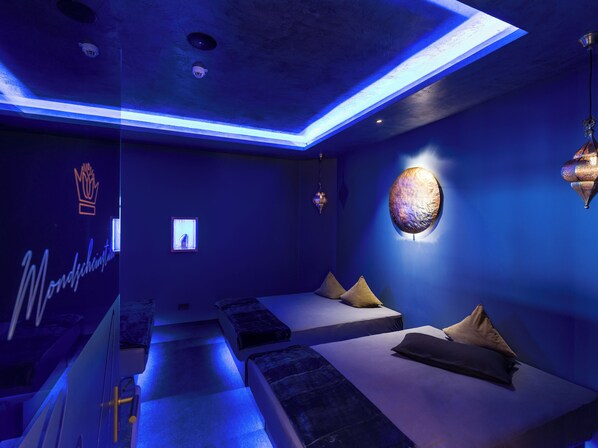 A modern room with a blue-lit ceiling, a wall-mounted spherical light, and a bed with pillows. - Hotel Panorama Royal (Bad Haering)