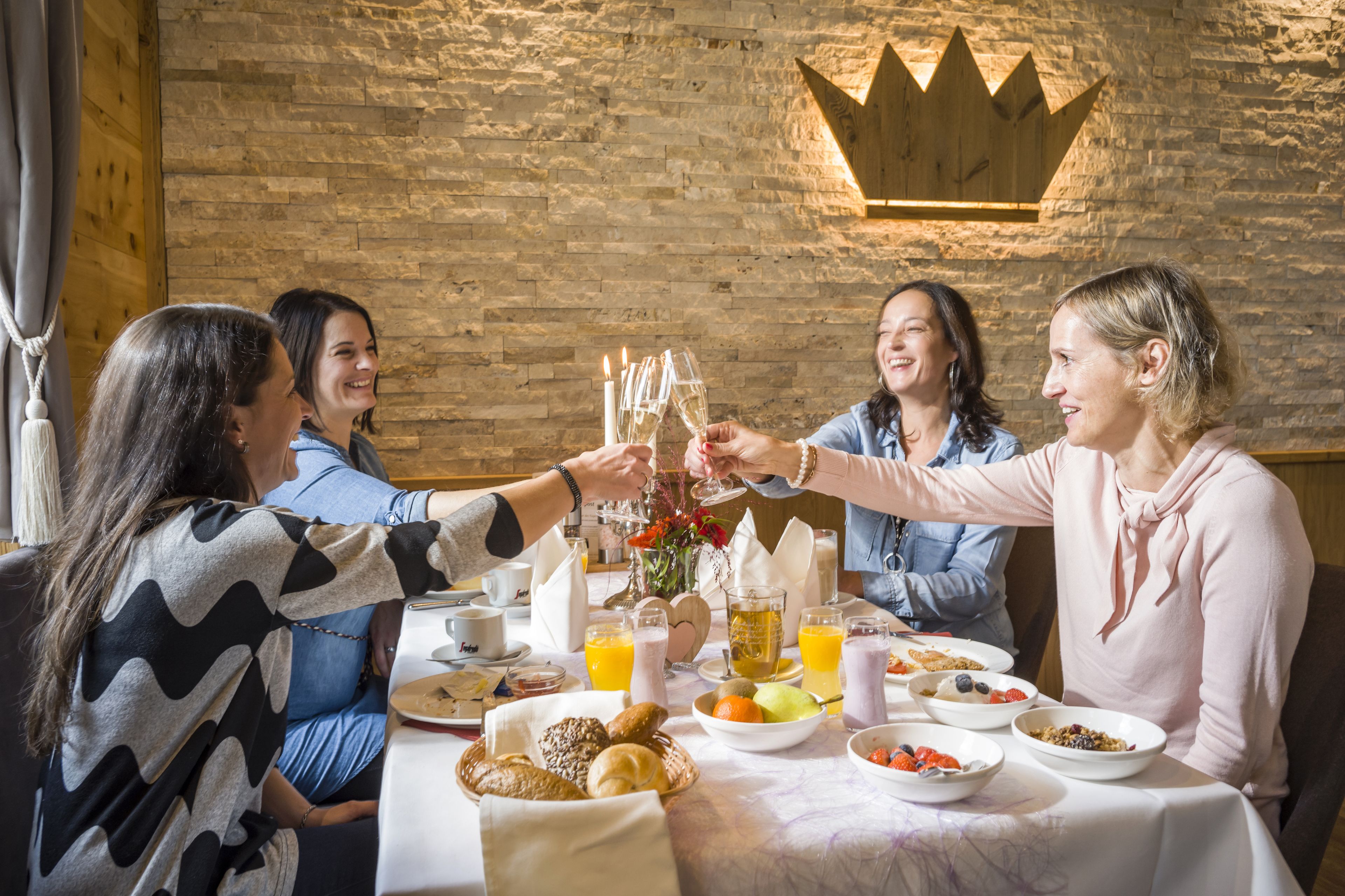 Un grupo de personas brindando en una mesa con alimentos y bebidas para el desayuno.