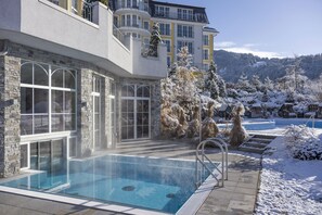 Un edificio moderno con piscina, fachada de piedra y paisaje nevado.