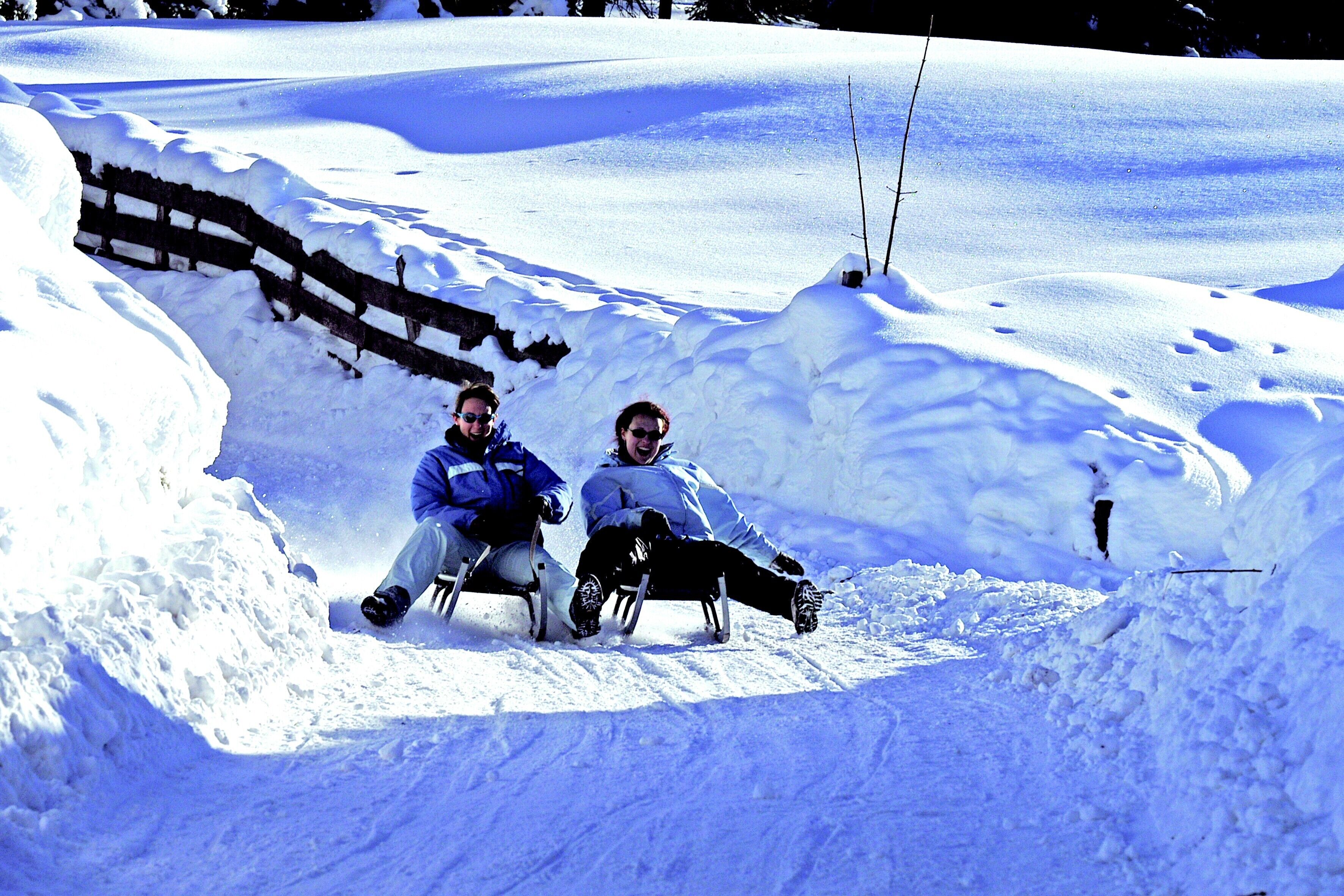 Two people sledding down a snowy slope.
