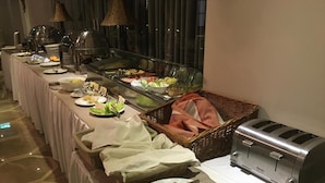 A buffet setup with various food items, a toaster, and baskets. - Hotel Capitulum (Gyor)