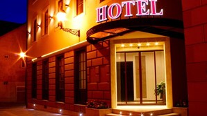 A hotel entrance with a prominent 'HOTEL' sign, a set of steps leading up to the entrance, and a well-lit facade. - Hotel Capitulum (Gyor)