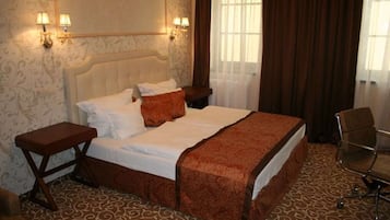 A hotel room with a large bed, two bedside tables, a chair, and a window with curtains.