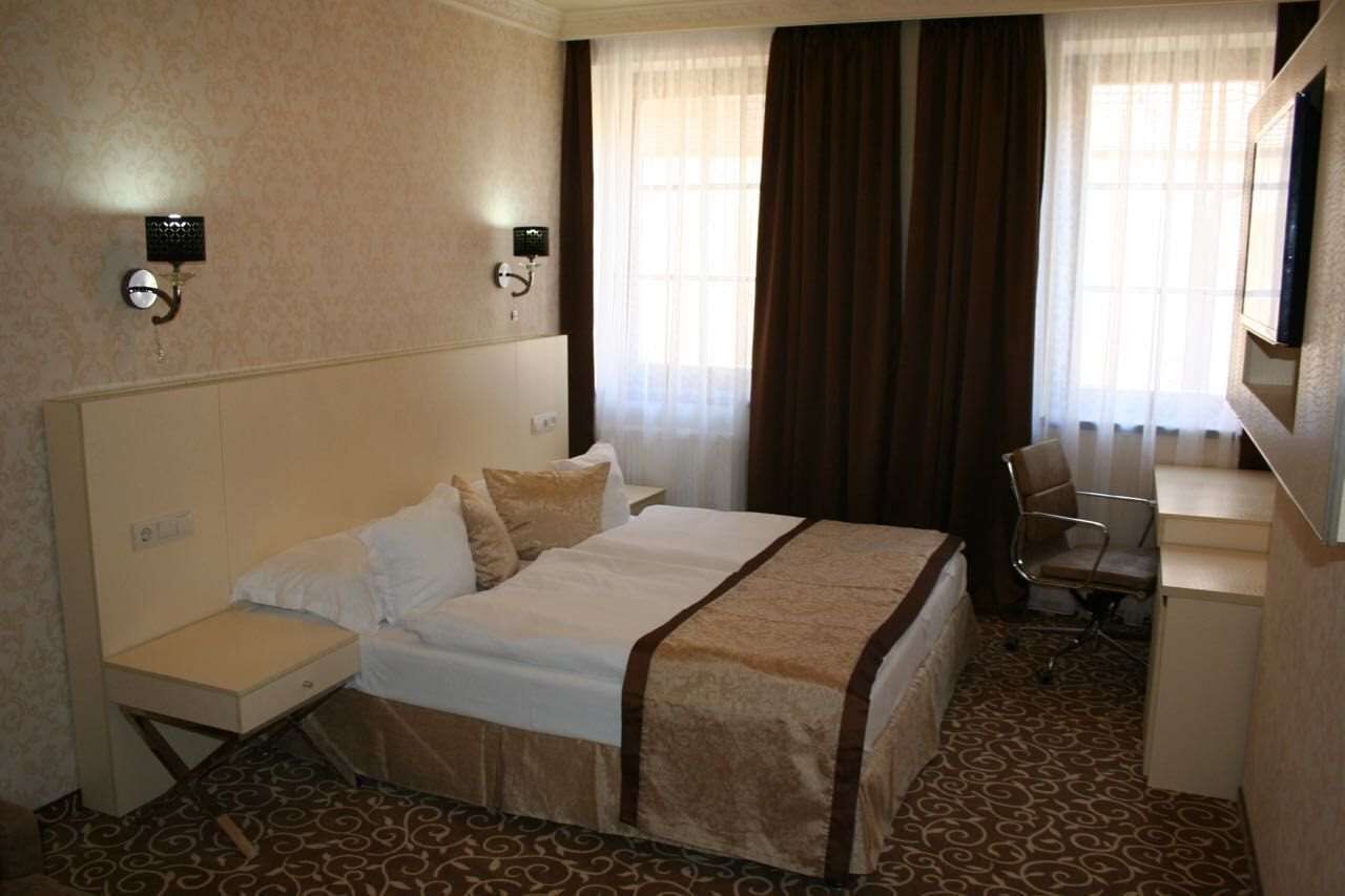 A hotel room with a bed, a desk, a chair, and a television.