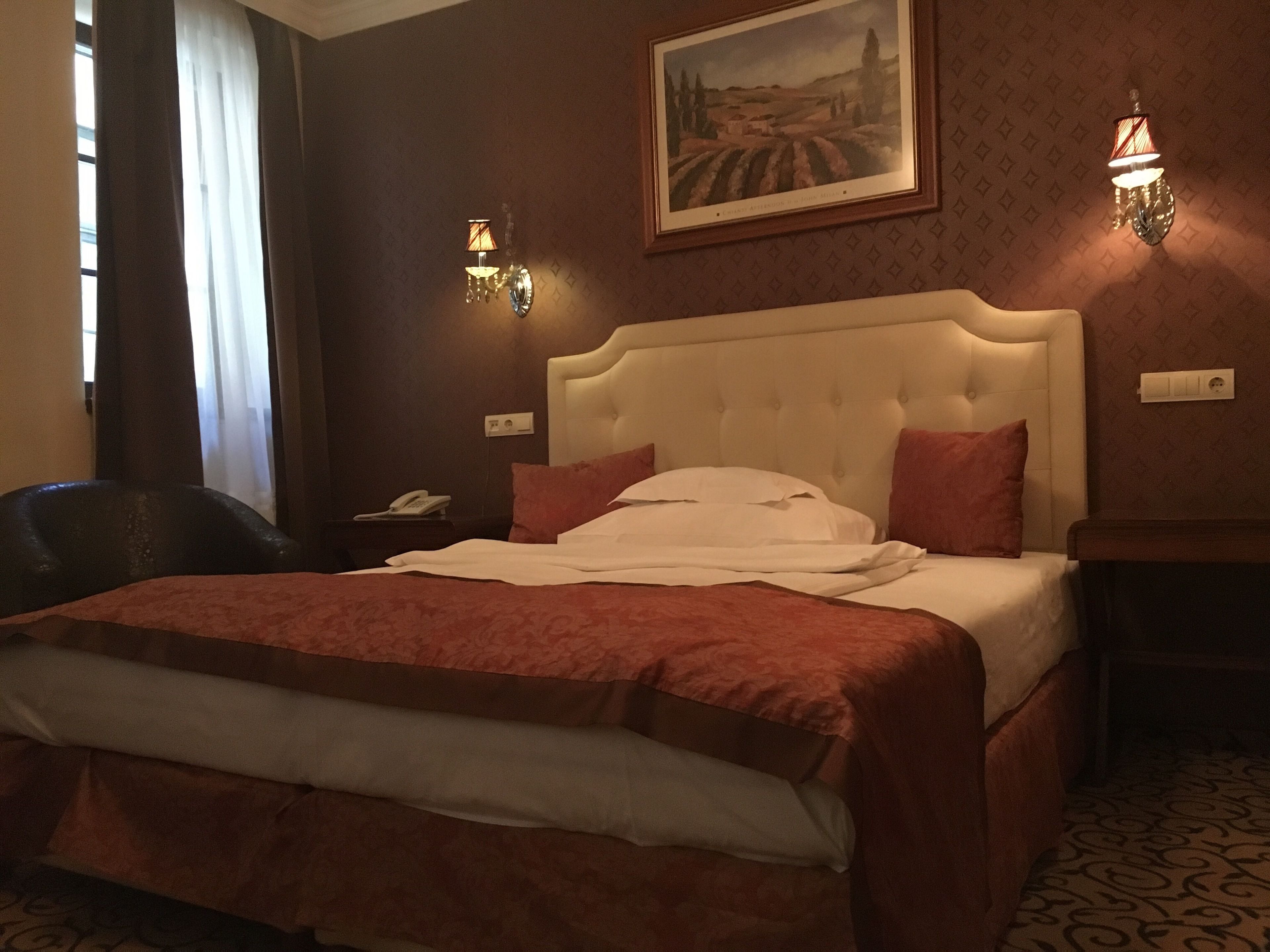 Une chambre d’hôtel avec un grand lit, une chaise, une table de chevet et un tableau au mur.
