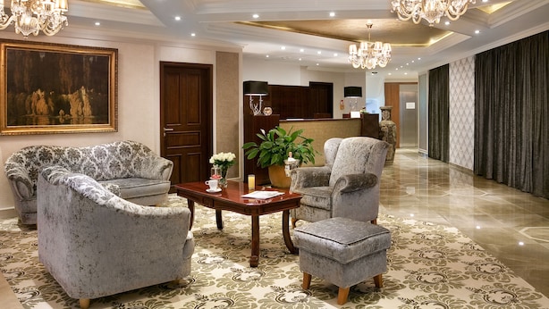 A spacious lobby with a large painting, elegant chandeliers, and plush seating. - Hotel Capitulum (Gyor)