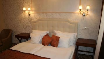A neatly made bed with white and brown bedding, two bedside tables, and wall-mounted lamps.