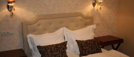 A neatly made bed with a tufted headboard, two bedside tables, and wall-mounted lamps.