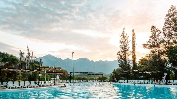 A swimming pool with lounge chairs and a view of mountains in the background.