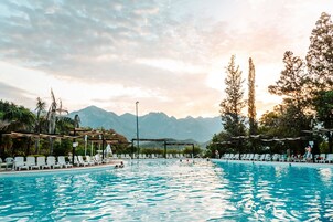 Una piscina con sillones de descanso y vistas a montañas al fondo.