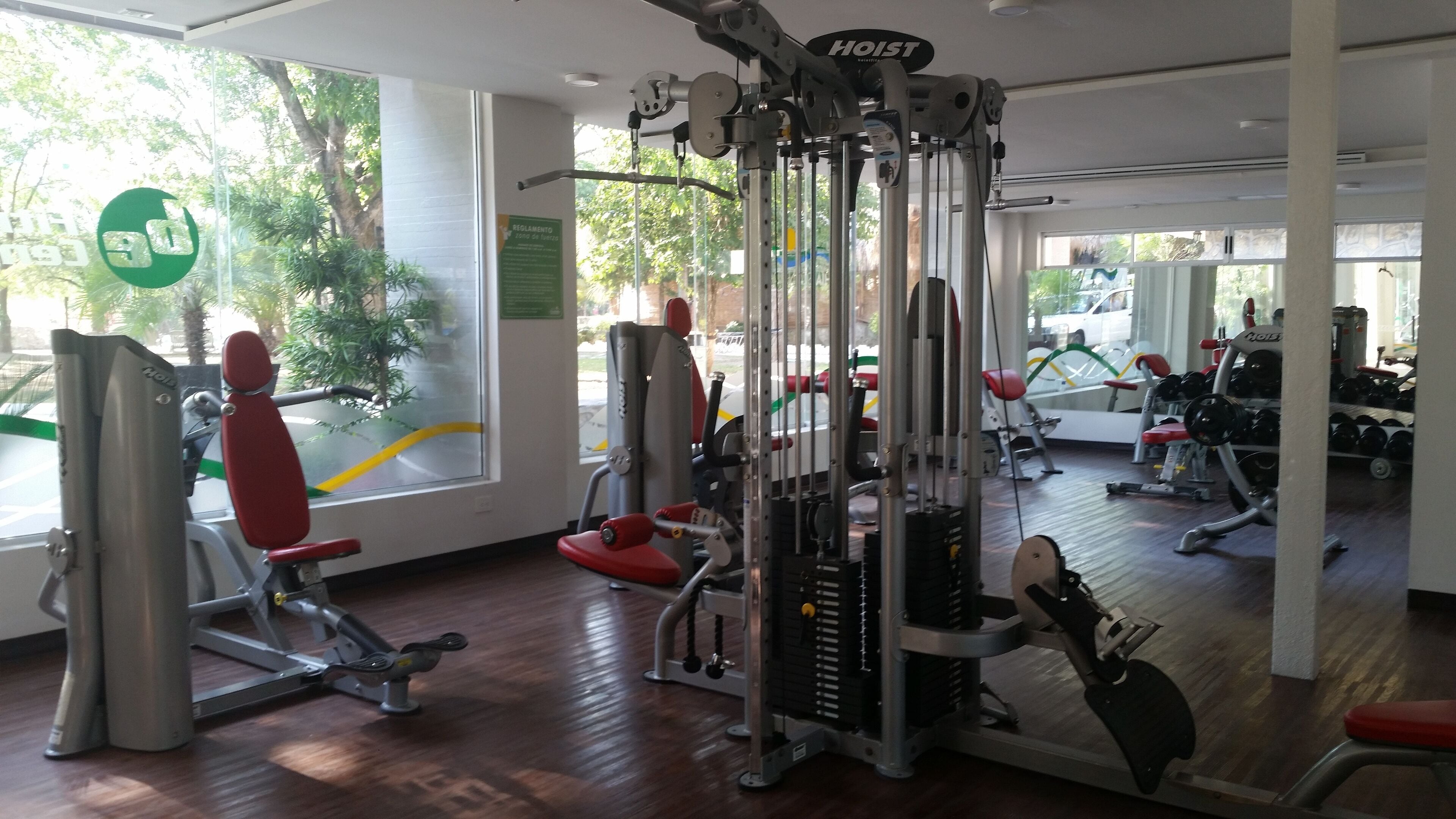 Een sportschool met diverse fitnessapparaten, grote ramen en uitzicht op het omliggende landschap.