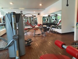 Un gimnasio con diferentes equipos de ejercicio, incluyendo máquinas de pesas y mancuernas.