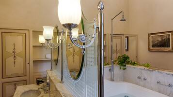 A bathroom with a marble sink, a bathtub, a shower, and a wall-mounted mirror.