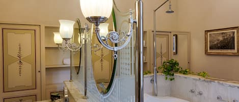 A bathroom with a marble sink, a bathtub, a shower, and a wall-mounted mirror.