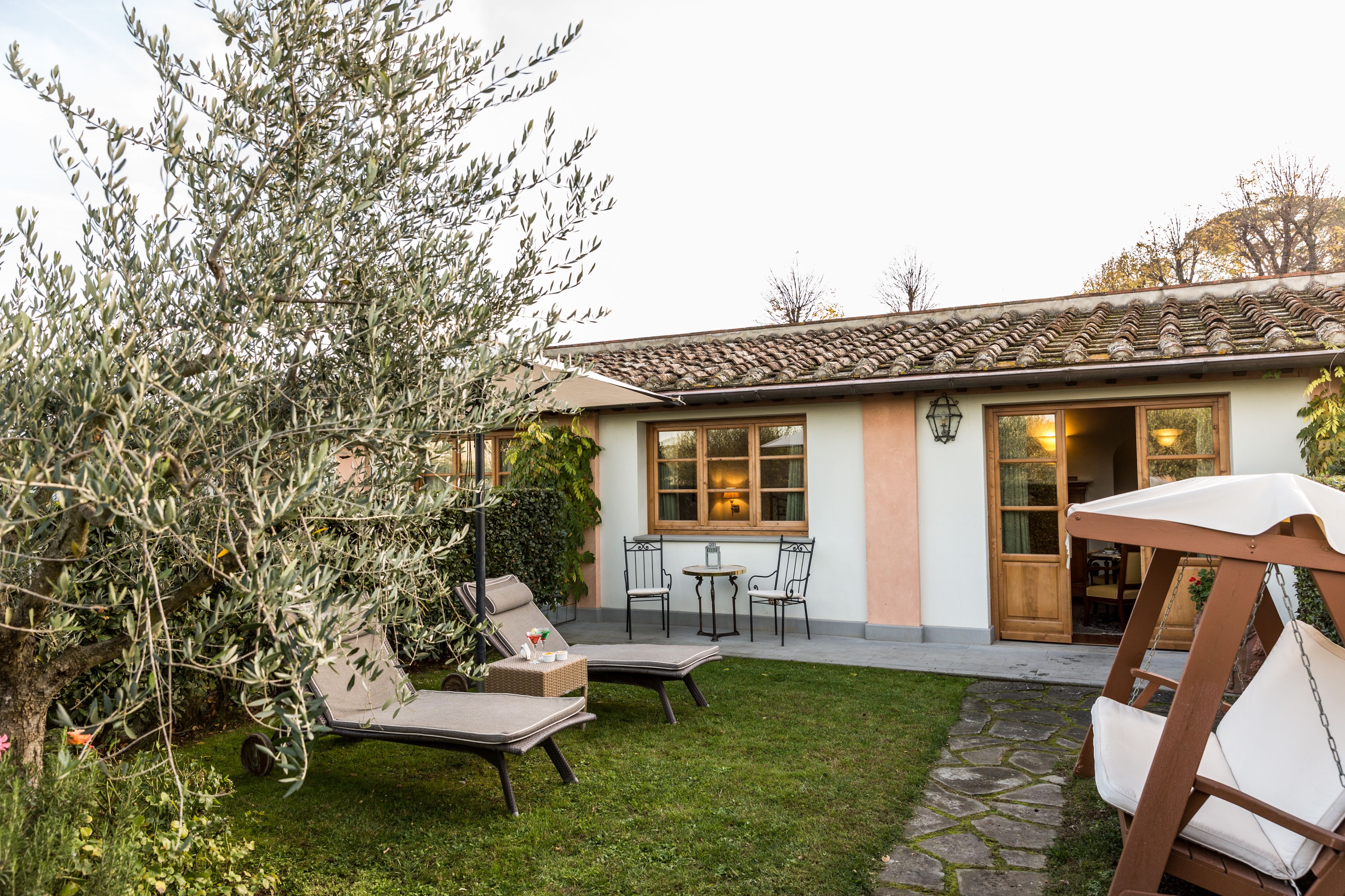 Une terrasse avec deux fauteuils de jardin, une petite table et un fauteuil suspendu.