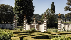 A formal garden with geometric hedges, statues, and urns on pedestals. - Villa Olmi Firenze (Bagno a Ripoli)