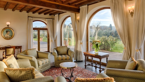 A spacious living room with a high ceiling, comfortable seating, and large windows offering a view of the outdoors. - Villa Olmi Firenze (Bagno a Ripoli)