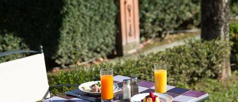A table set outdoors with a meal, a glass of orange juice, and a bottle of water.