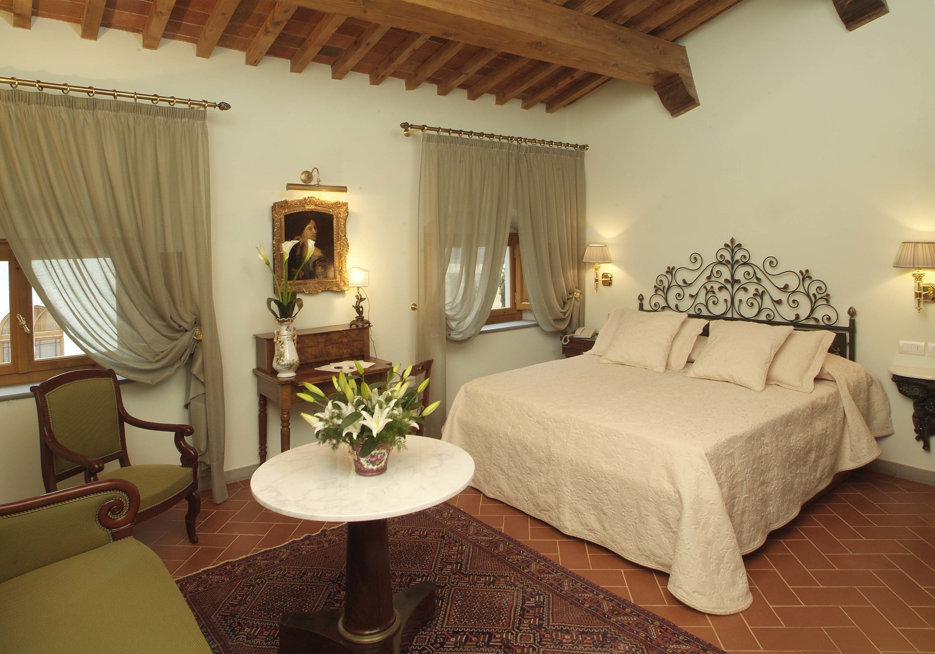 Ein Schlafzimmer mit Bett, Stuhl, Tisch und einem Bild an der Wand.