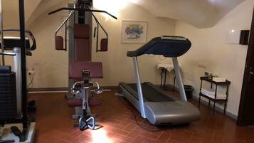 Un gimnasio en casa con cinta de correr, banco de pesas y máquina de ejercicios.