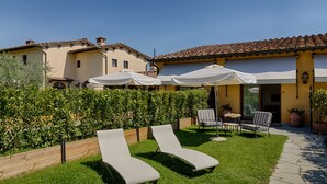 Un patio con dos sillones, una mesa y sombrillas.