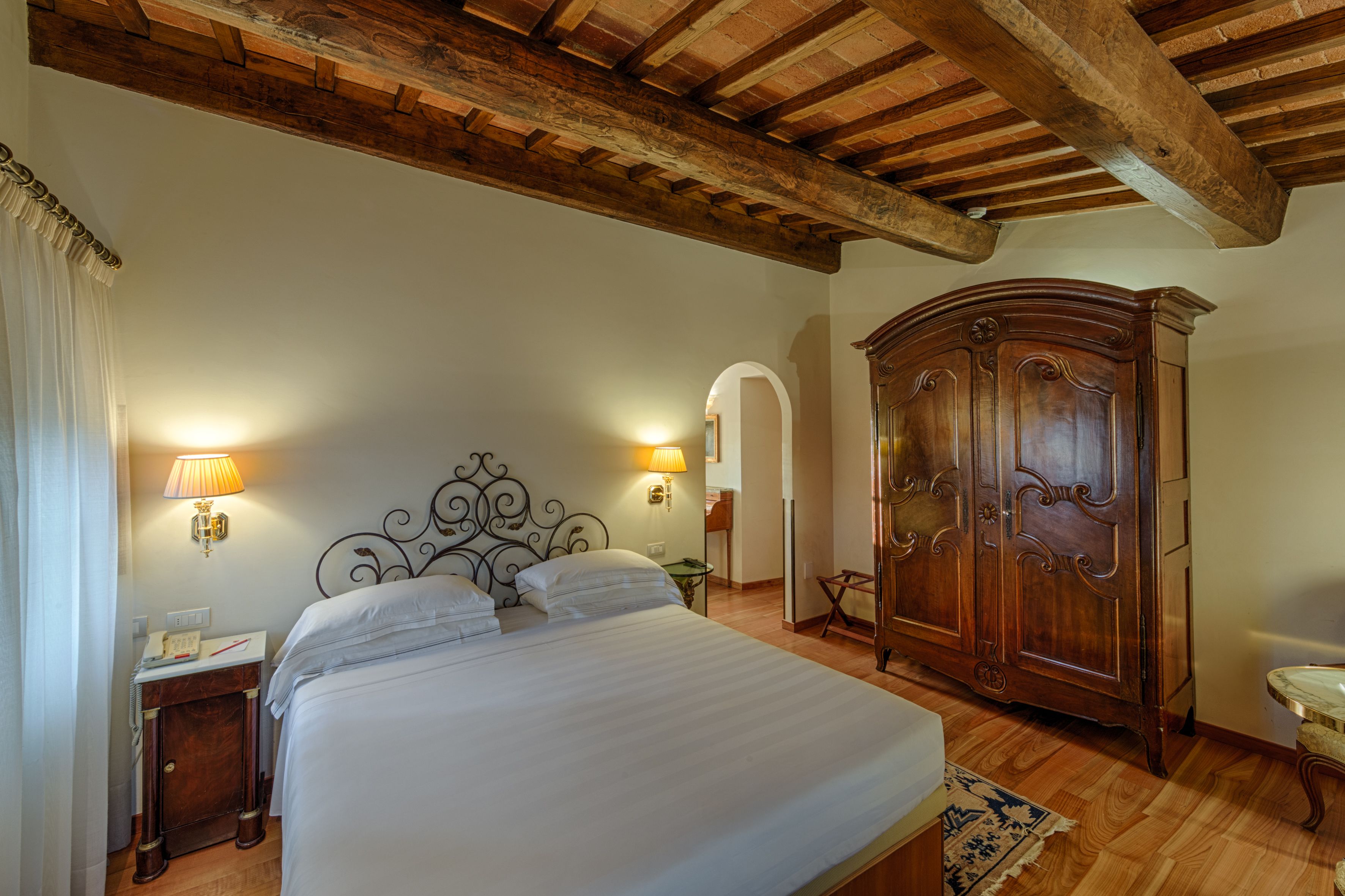 Una camera da letto con un letto grande, travi in legno a soffitto, un armadio e due lampade a parete.