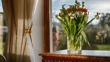 Un jarrón con flores sobre una mesa de madera cerca de una ventana con cortinas.