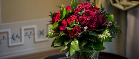 A bouquet of red roses in a clear glass vase on a black tray with gold trim.