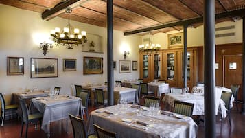 Un restaurante con varias mesas dispuestas para comer, sillas de madera y un candelabro.