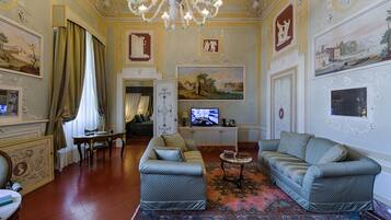 Een ruime woonkamer met twee banken, een televisie en een kroonluchter.