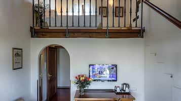 A cozy living room with a wooden ceiling, a sofa, a TV, and a dining area with a table and chairs.