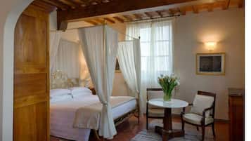 Ein Schlafzimmer mit einem Himmelbett, einem runden Tisch mit Stuhl und einem kleinen Schrank.