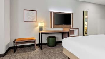 Une chambre d’hôtel comprenant un lit, un bureau avec une chaise, une télévision, une lampe et un tableau encadré au mur.