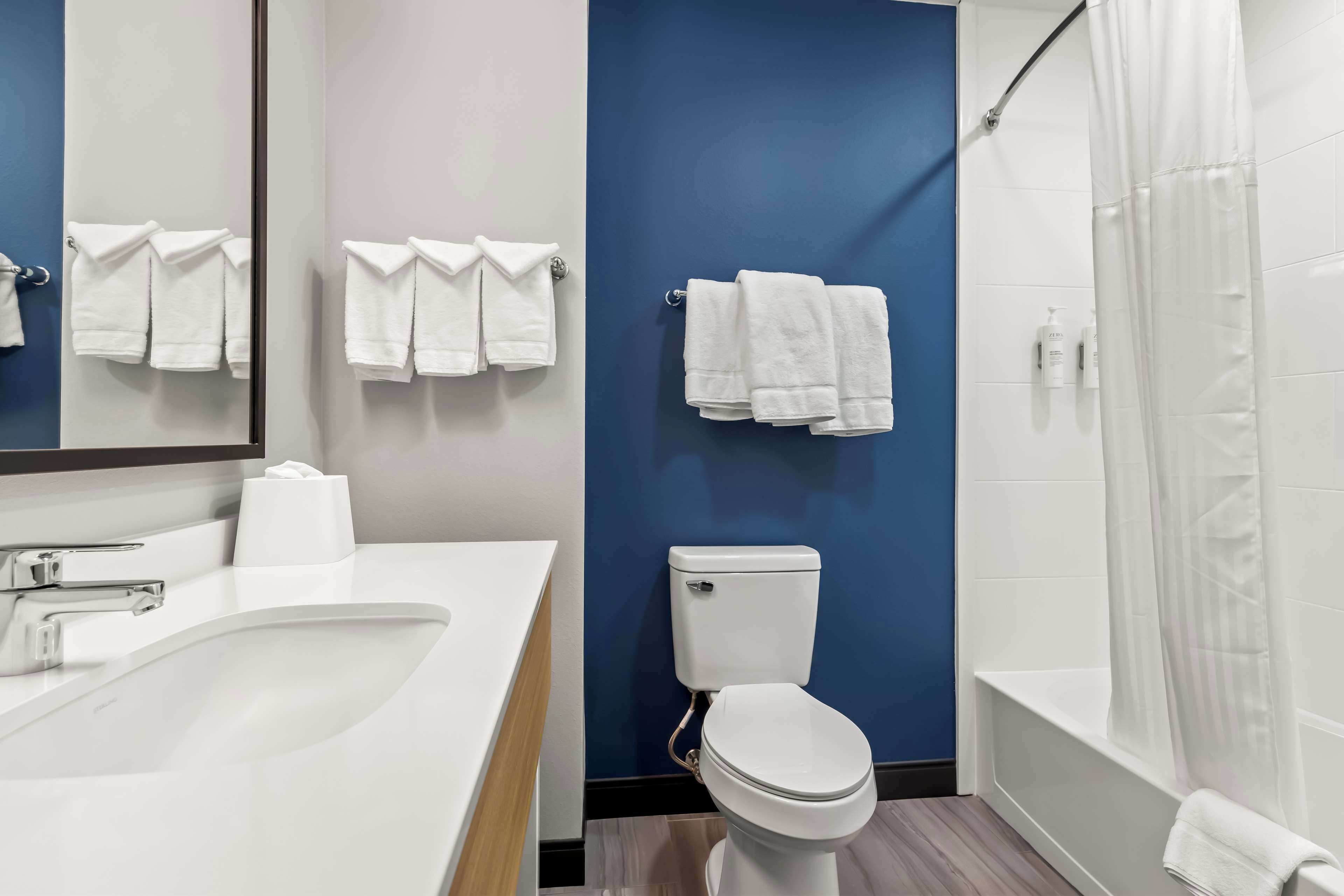 A modern bathroom with a white sink, a toilet, and a shower area.