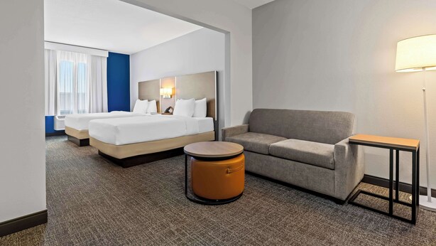 A hotel room with a bed, a sofa, a round table, and a lamp. - Spark by Hilton Catoosa (Catoosa)