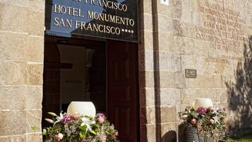 Ingången till hotellet Convento San Francisco Hotel Monumento, med en röd matta och blomsterarrangemang.