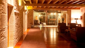 A wooden interior with a stone wall, a carpeted hallway, and a seating area with a table and chairs.