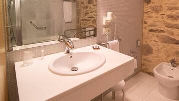 Un baño con lavamanos blanco, espejo, ducha y bidé.