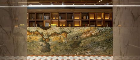 A reception area with a marble counter, wooden shelving with books, and a patterned floor.