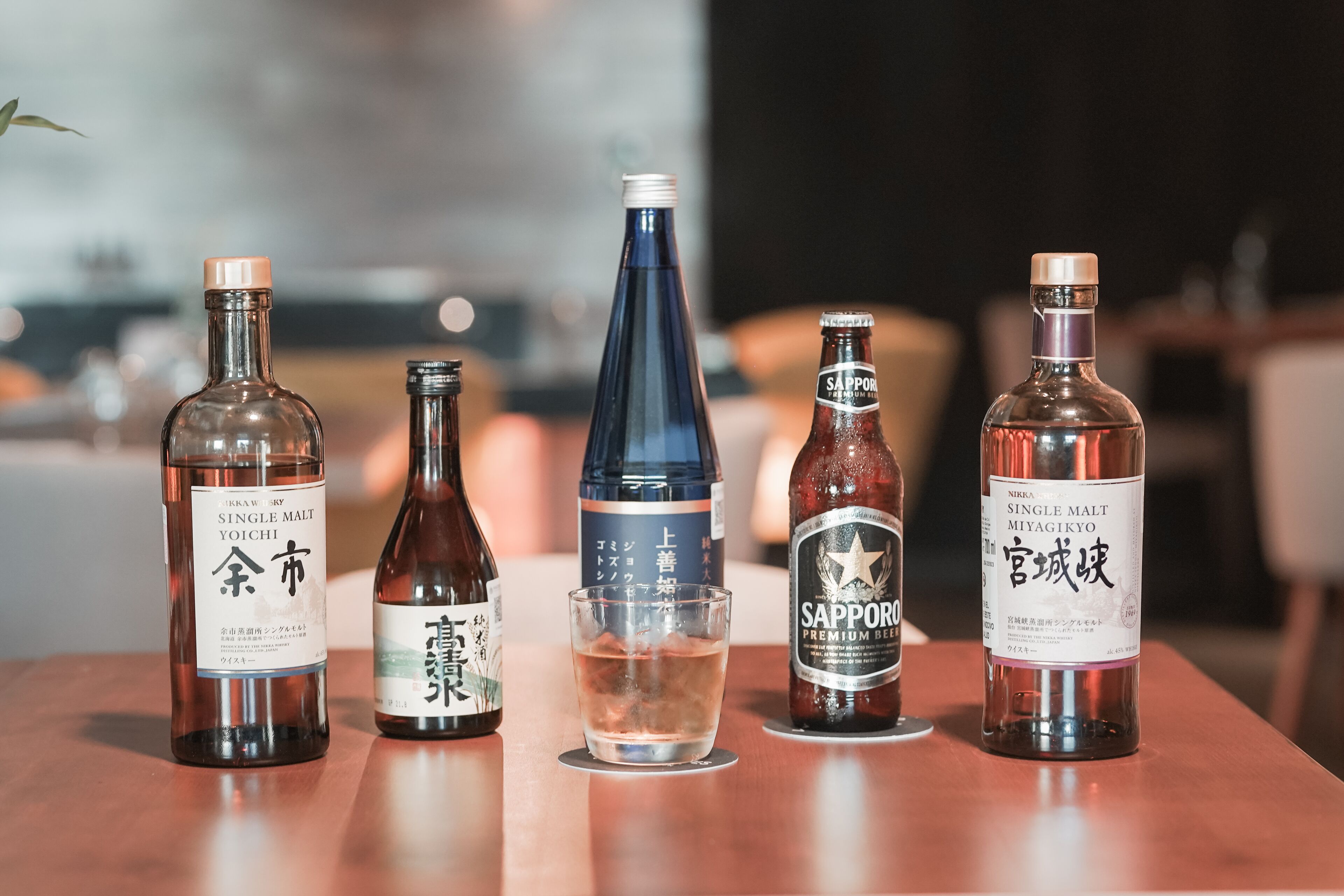 Four bottles of beverages on a wooden table.