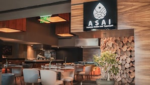 A restaurant interior with wooden walls, a sign reading "ASAI Japanese Cuisine and Teppanyaki", and a stack of wood logs. - Villa Mercedes Merida, Curio Collection by Hilton (Mérida)
