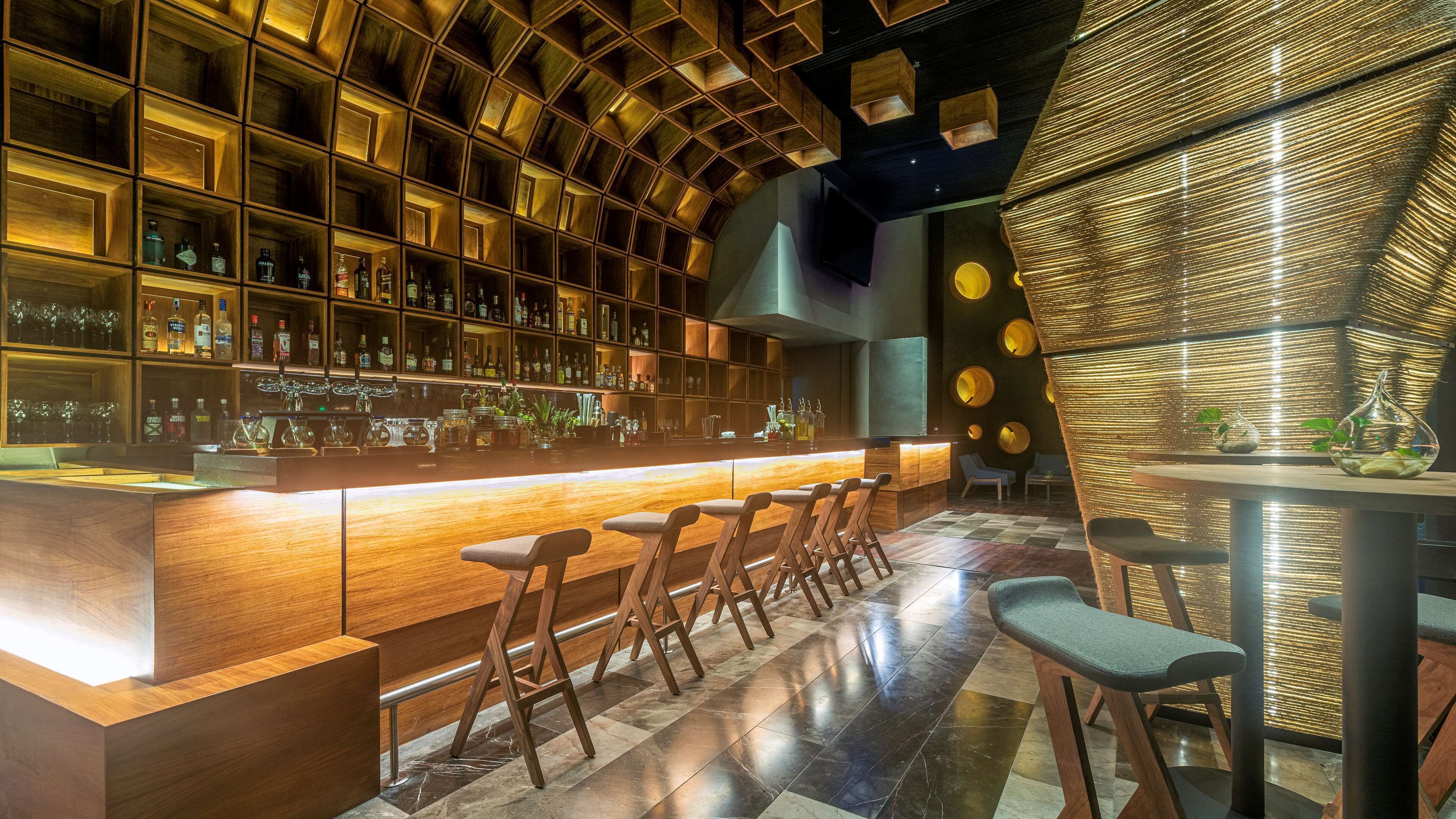 A bar area with wooden shelves stocked with bottles, a bar counter, and seating.
