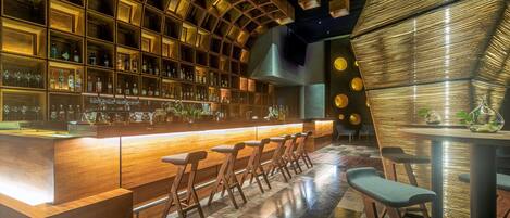 A bar area with wooden shelves stocked with bottles, a bar counter, and seating.